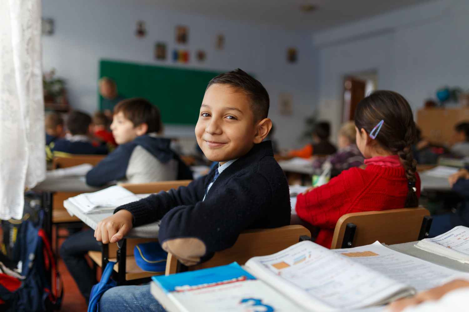 A high school student in 10th or 12th grade smiling in class, engaging with in-person learning, offering a contrast to the flexibility of distance education courses.