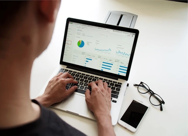 Hands typing on a laptop displaying analytics dashboards, representing practical knowledge gained from an online certificate course in digital marketing.