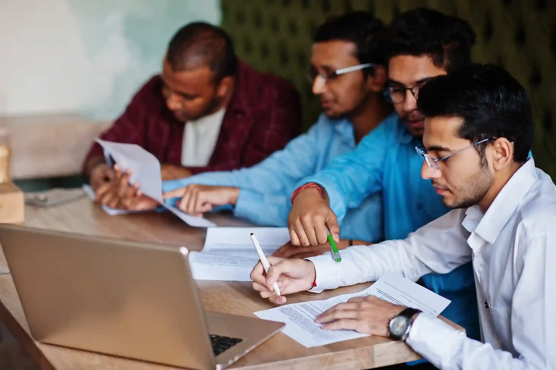 A group of young students collaborating on study materials in a modern learning environment, highlighting the interactive and flexible scope of distance education.