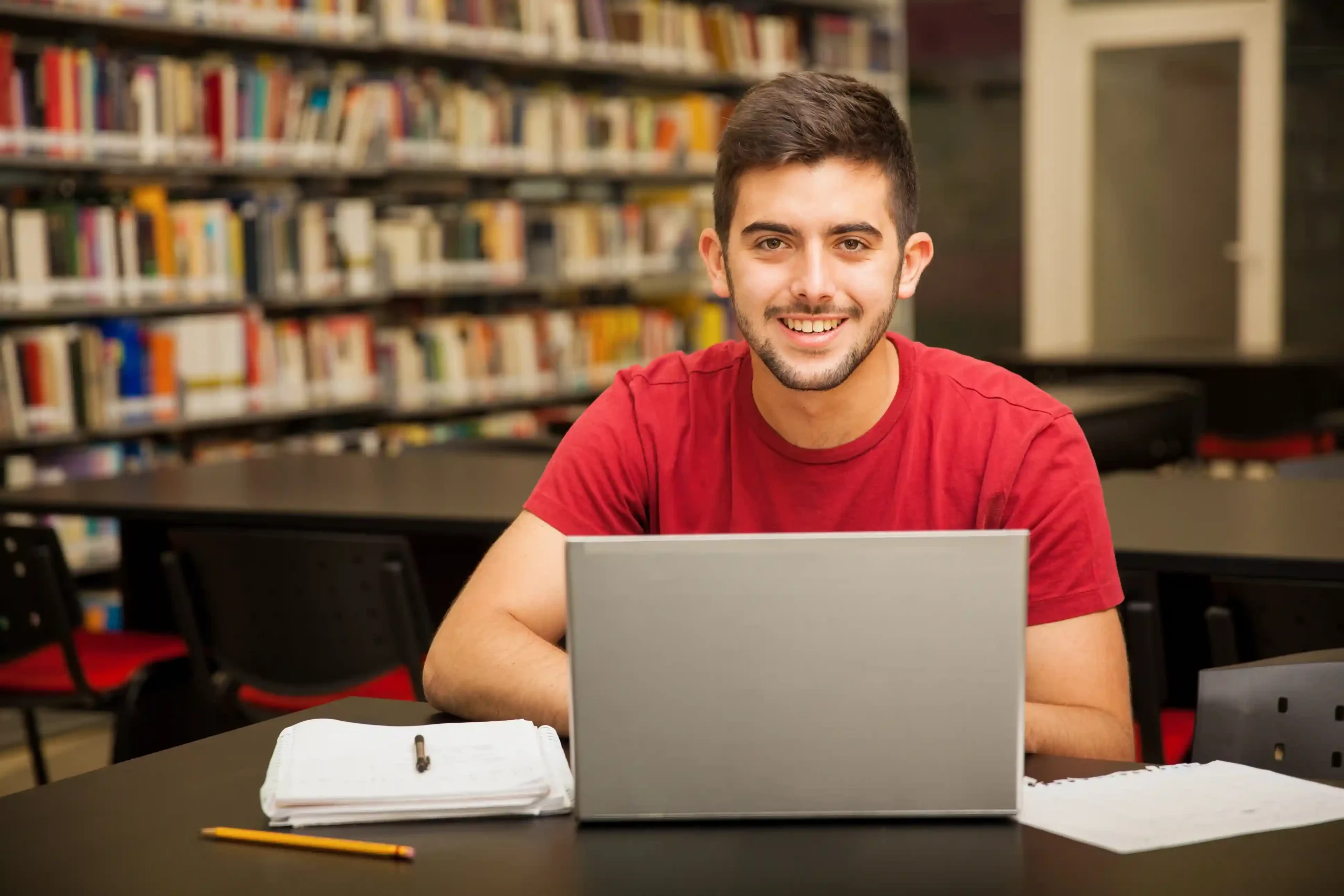 A student in a library using a laptop, researching distance education courses after 12th to explore career opportunities in various fields.